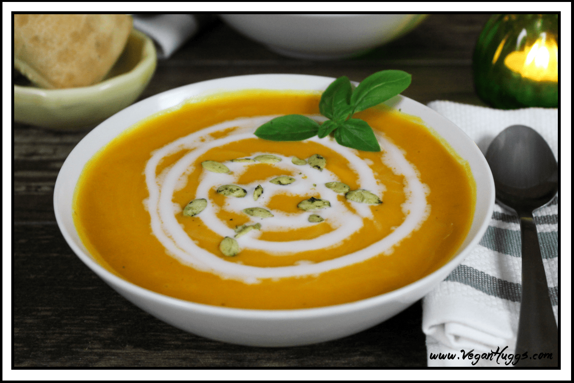 White bowl filled with vegan sweet potato soup with fresh basil on top.