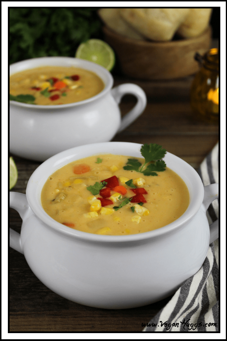 Two bowls of potato corn chowder with bread in the background. 