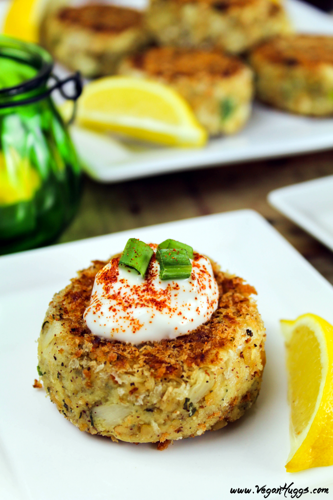 Vegan Crab Cakes on a white plate. Topped with tartar sauce and green onion. 