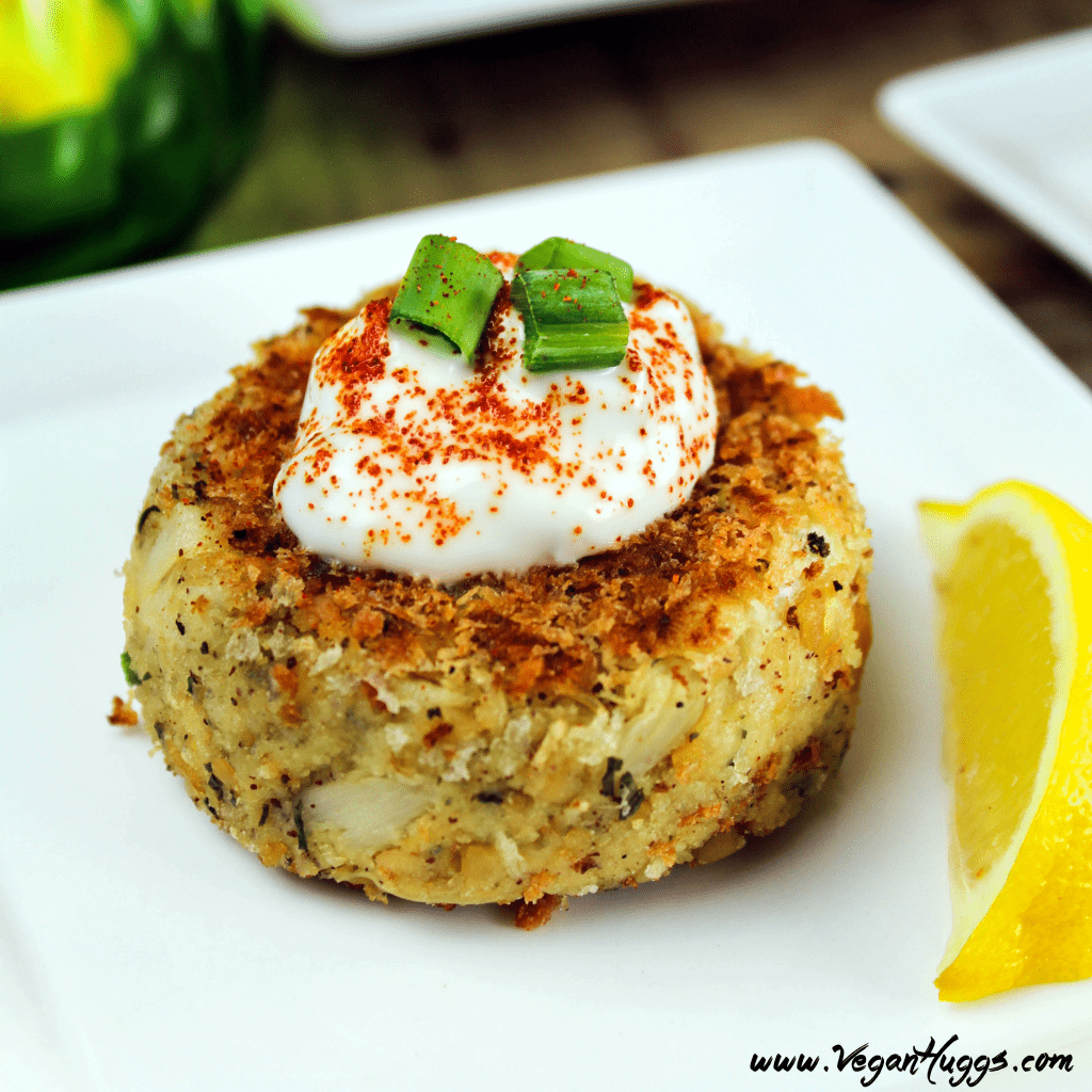 Closeup view of Vegan Crab Cakes on a white plate with a lemon wedge. 