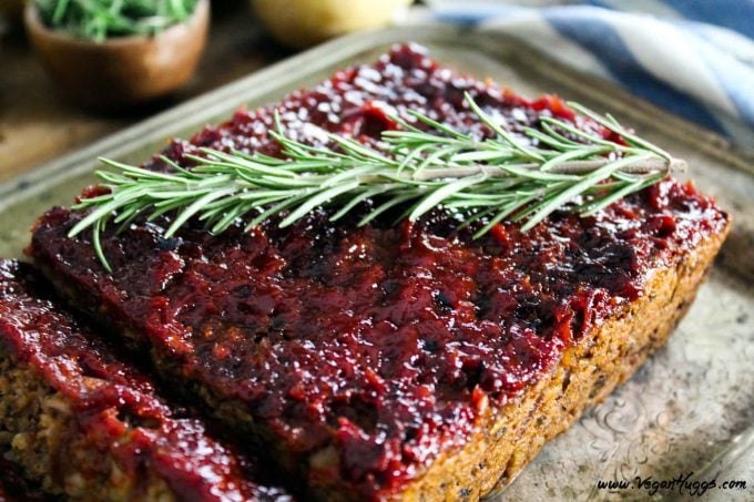 Overhead view of vegan meatloaf on a silver serving plate. Topped with ketchup glaze and fresh rosemary. 