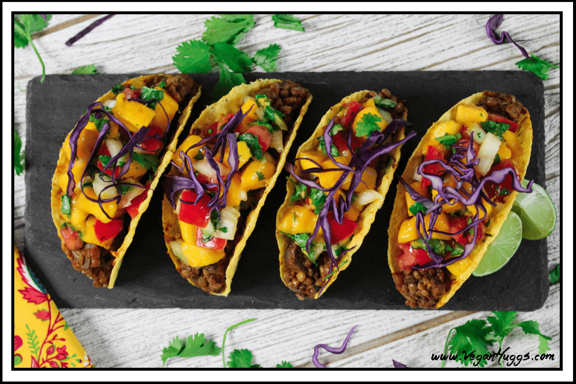 Overhead view of 4 mushroom tacos on a slate board. 