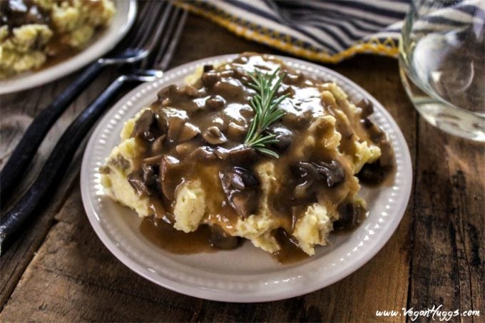 Creamy mashed Potatoes & Mushroom Gravy on a plate with wine glass on the side. 