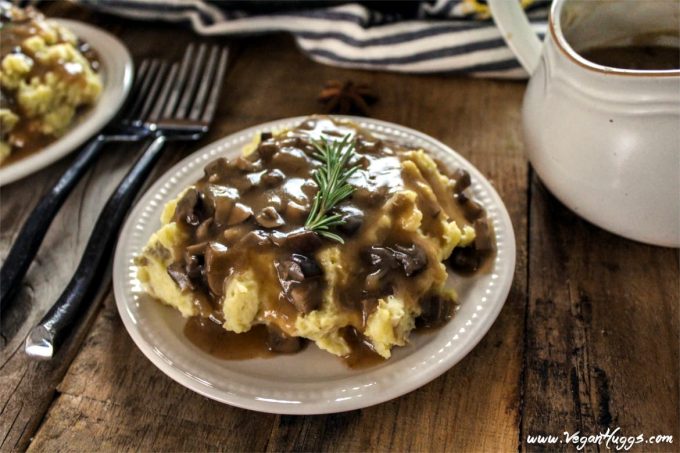 Mashed Potatoes & Mushroom Gravy with gravy boat in the background. Two forks in the middle. 