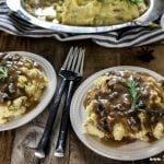 Two plates of creamy mashed potatoes and mushroom gravy