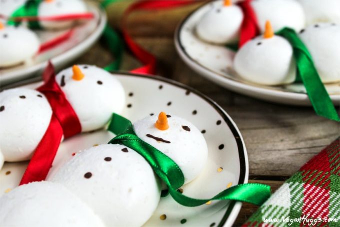 Side view of snowmen vegan meringue cookies on polka dotted plates. 