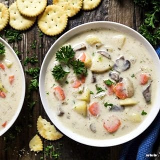 Two bowls of vegan clam chowder on a wood table.