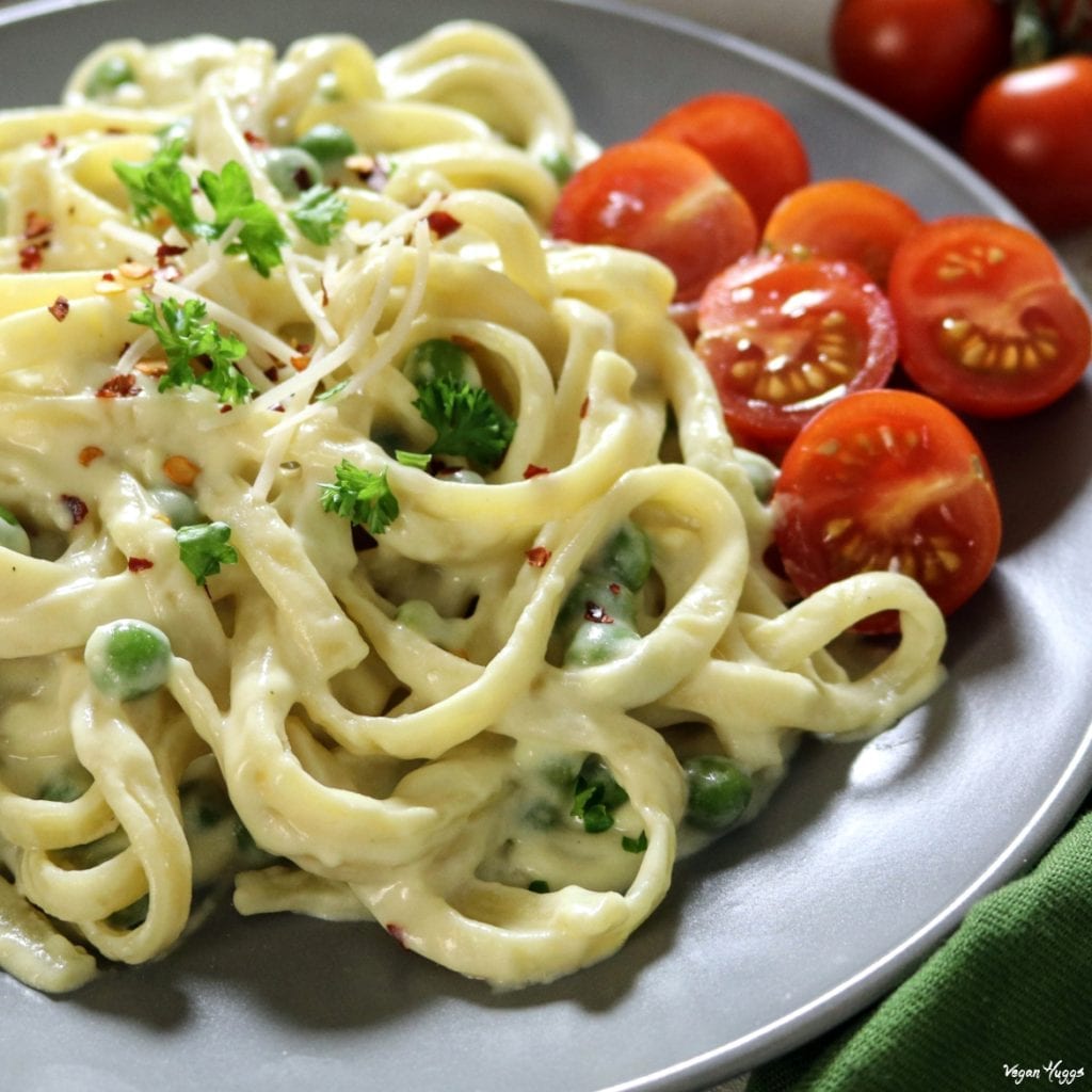 Closeup view of cooked pasta on a gray plate. Topped with parsley and red pepper. 