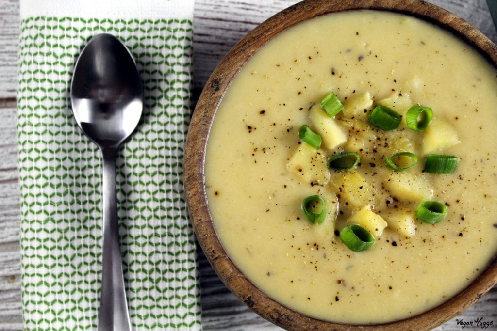 Vegan Potato Leek Soup in a wooden bowl with green napkin and spoon on the side.