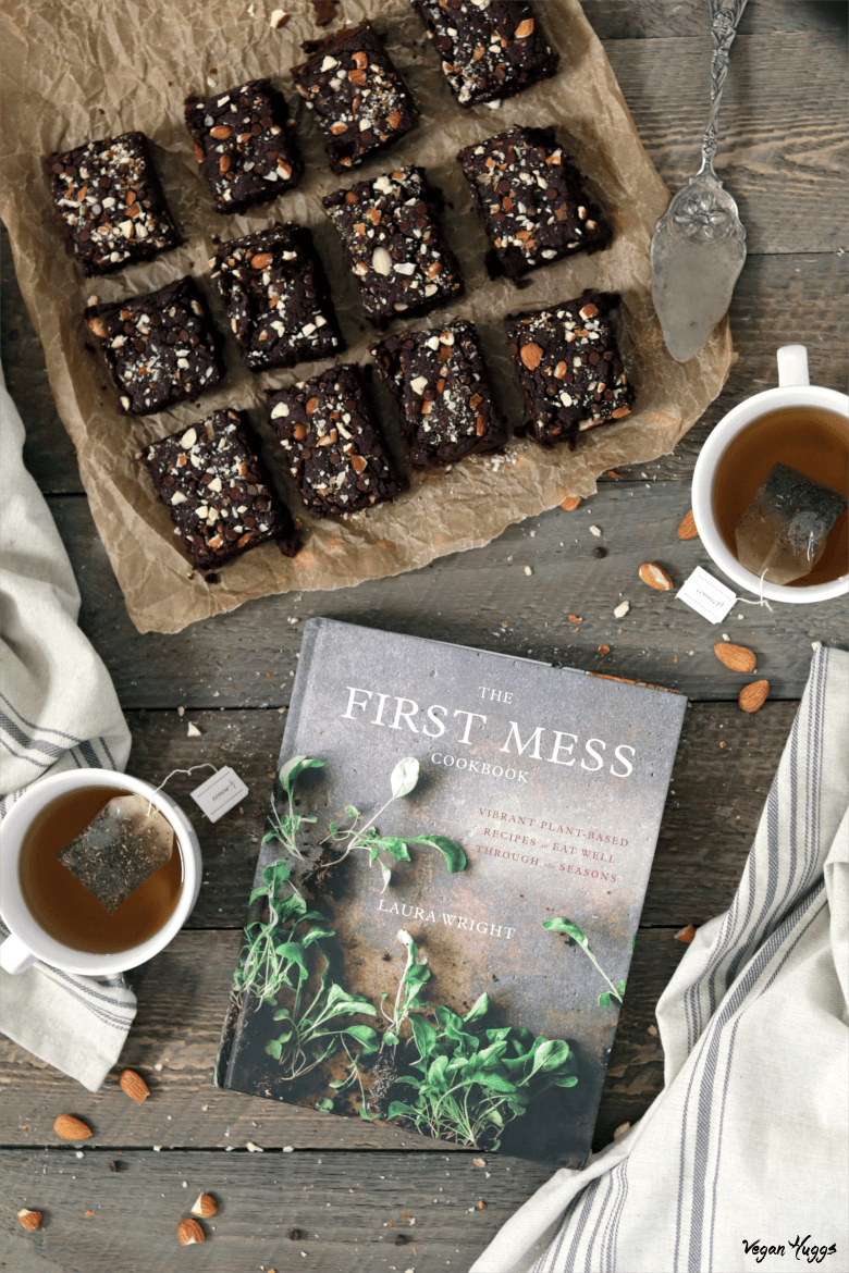 Overhead view of Fudgy Chocolate Brownies on parchment paper. Tea and cookbook on the side. 