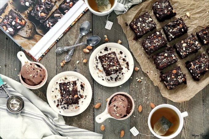 Overhead view of Fudgy Chocolate Brownies on parchment paper. Tea and ice cream on the side. 