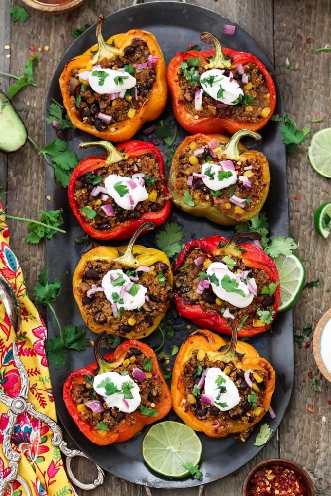 Vertical photo of 8 Quinoa Stuffed Peppers fully loaded with toppings. 