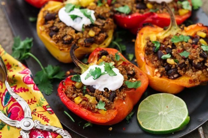 Closeup photo of 4 quinoa stuffed peppers. Topped with sour cream and cilantro. 