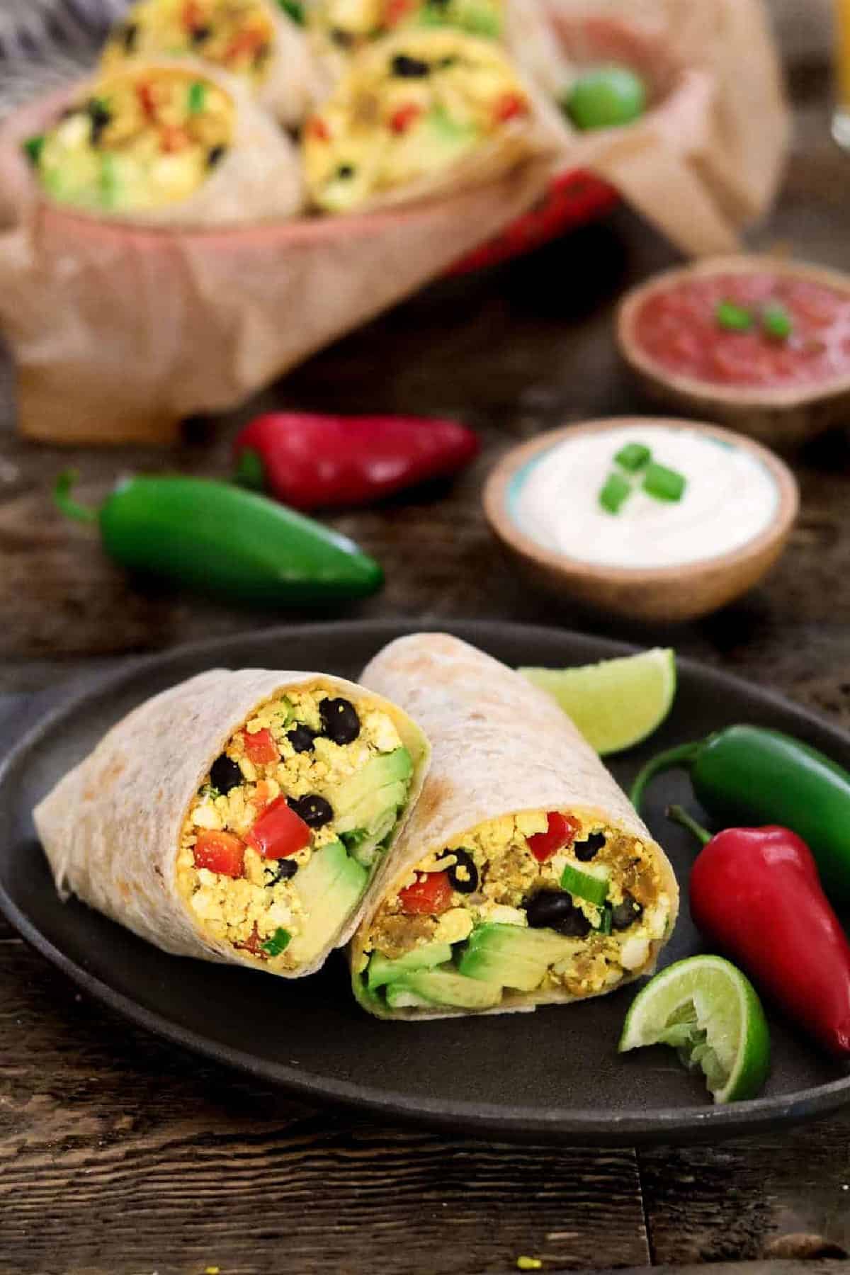 Slice burrito on a plate and a basket of burritos in the background. 