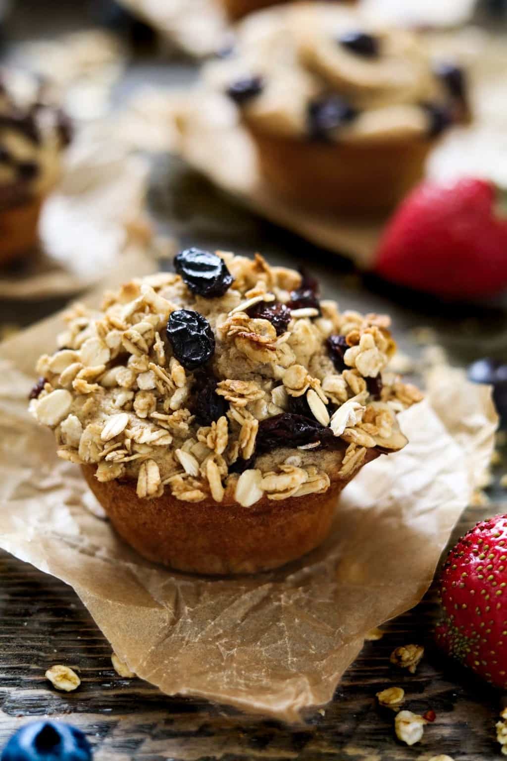 a vegan protein muffin on a piece of parchment paper with strawberries on the side. 