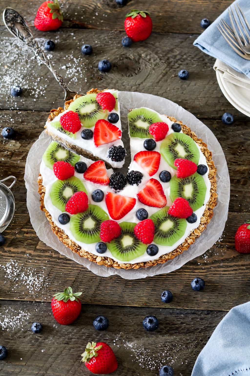 Overhead view of a fully assembled fruit pizza on parchment paper.