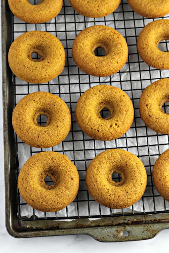 Fully baked vegan pumpkin donuts on a wire cooling rack. 