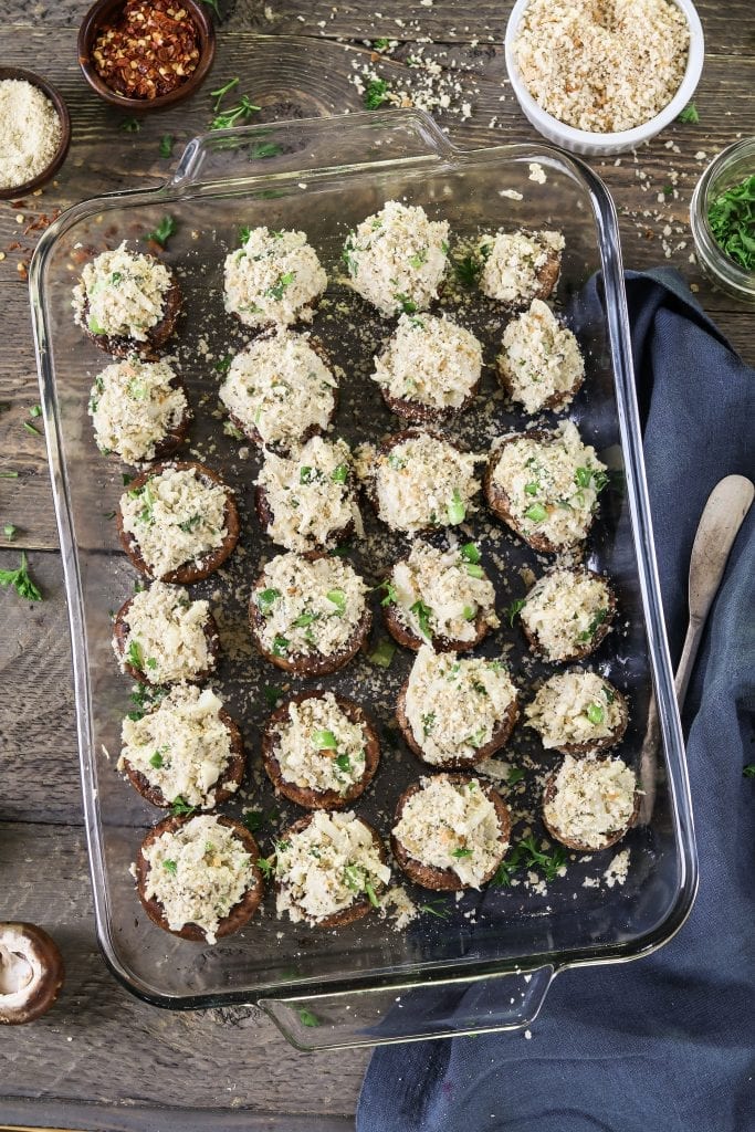 Glass baking dish filled with stuffed mushrooms before they go into the oven. 