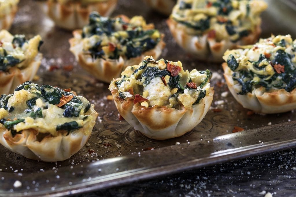 Fully baked spinach artichoke cups on a silver tray.