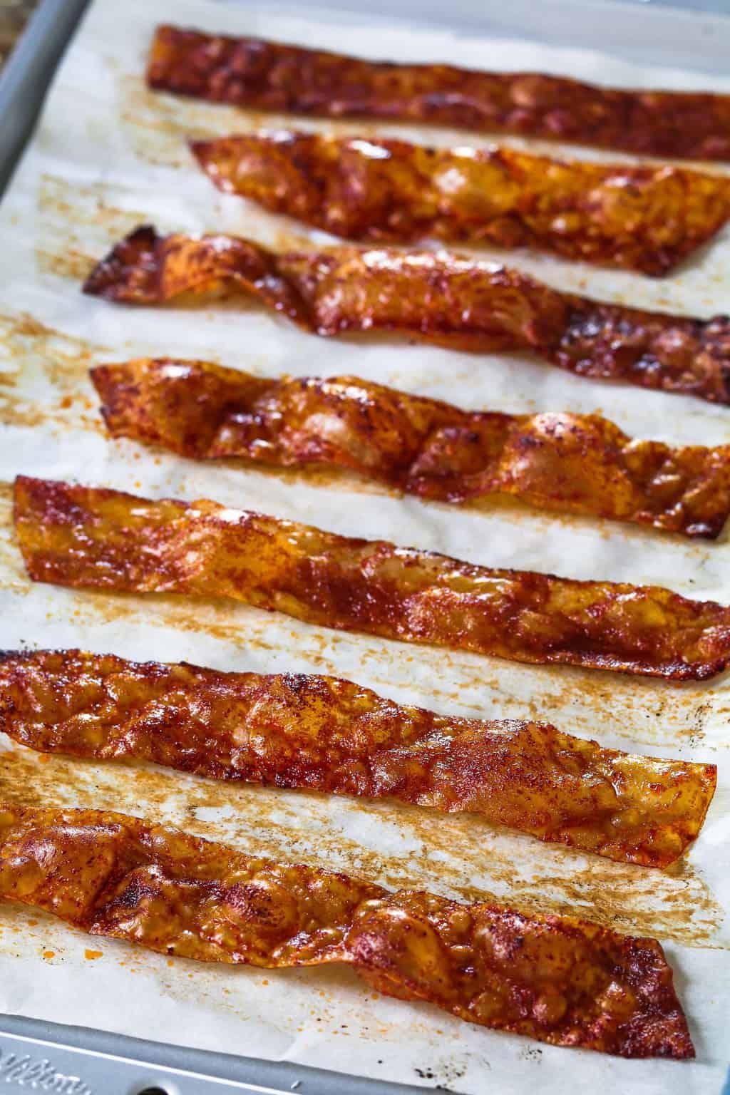 Vertical photo of cooked rice paper vegan bacon on a baking sheet.