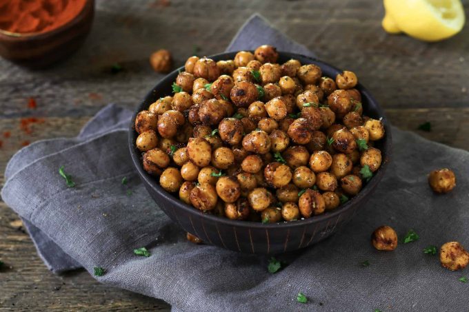 Horizontal photo of air fried chickpeas in a black bowl on top of grey napkin. 