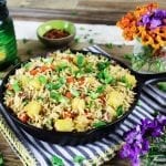 Rice in a skillet with flowers and green candle in the background. 