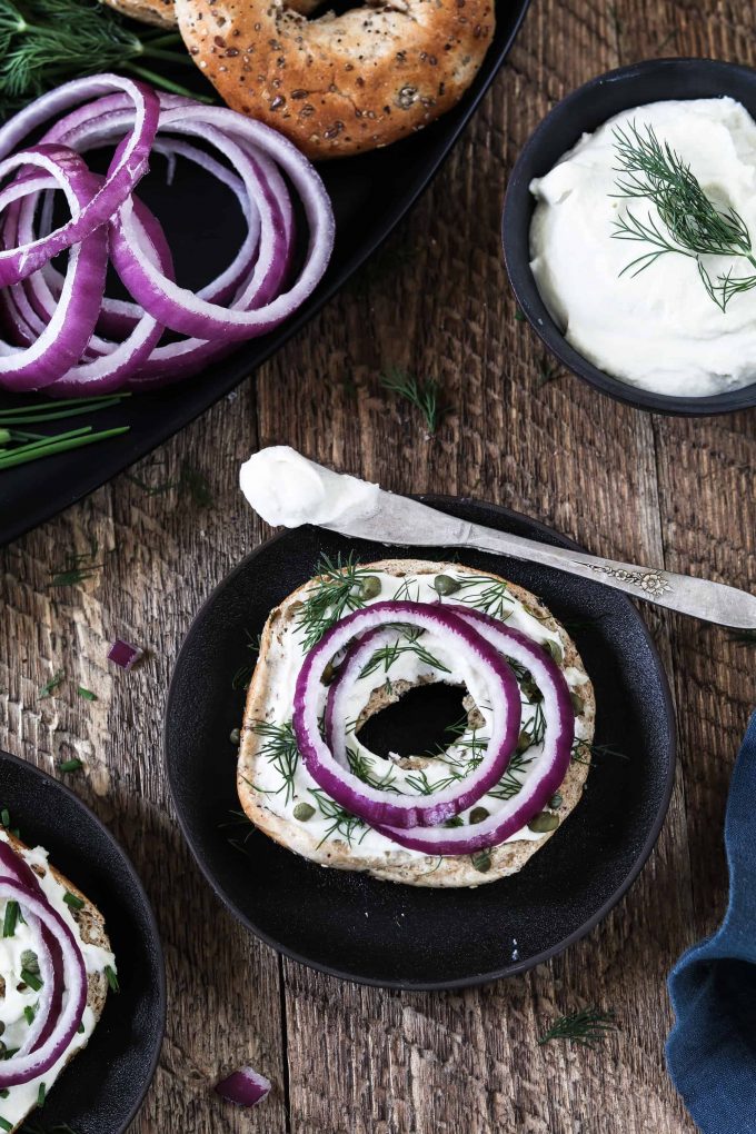 Open-faced bagel with cheese, slice red onion, capers and dill. 