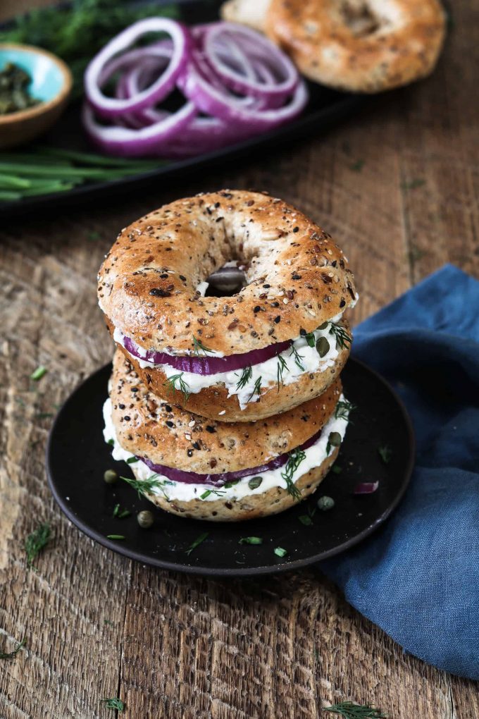 2 bagels stacked on top of each other with Almond Cream Cheese, red onion, dill and capers. 