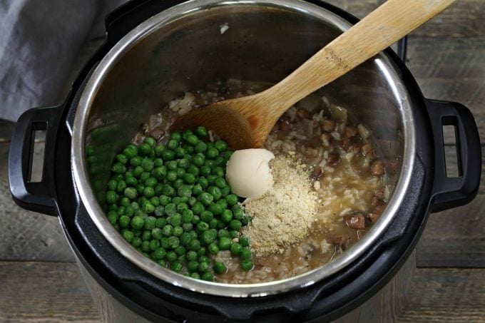 Adding the peas, vegan butter and vegan parmesan to the finished risotto. 