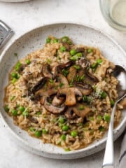 instant pot mushroom risotto in a white bowl with a spoon on the side.