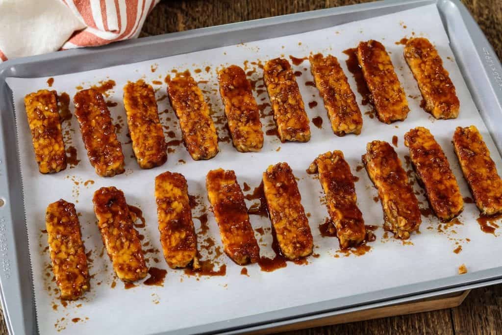 Baking pan lined with parchment paper and marinaded tempeh on top. Ready to go in oven. 