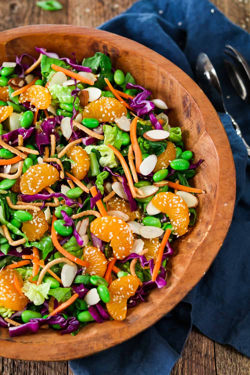 Wood bowl filled with asian chopped salad. Topped with oranges and sesame seeds. 