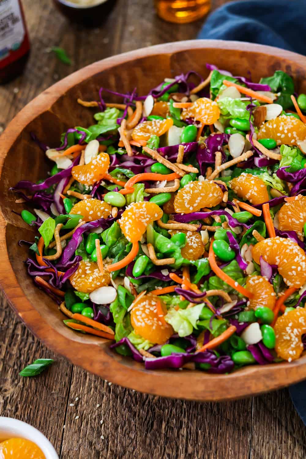 Wooden bowl filled with asian chopped salad. Dressing ingredients in the background.