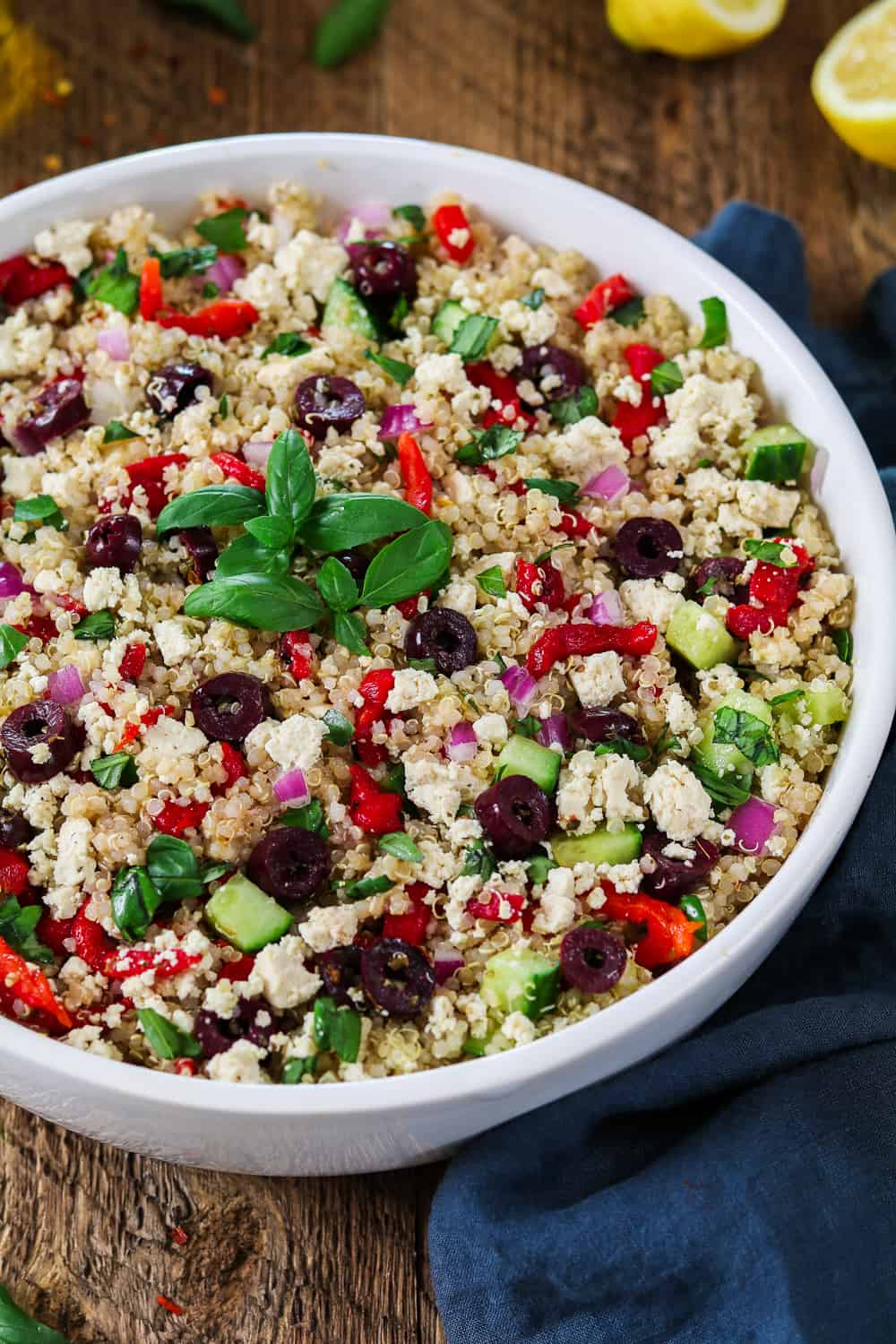 Mediterranean Quinoa Salad in a large white bowl, topped with fresh basil sprigs.