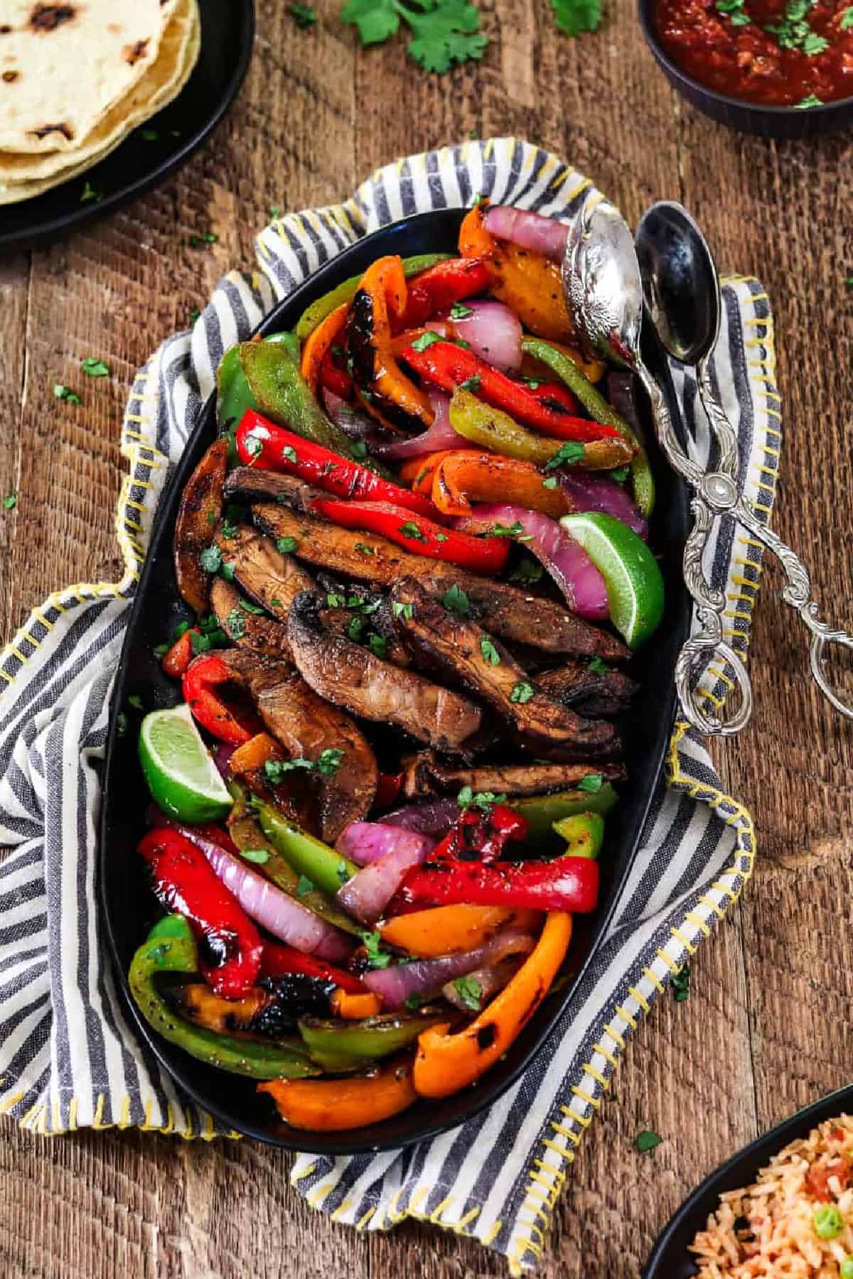 Get your weeknight sizzling In just 30 minutes with these Portobello Vegan Fajitas. They are spicy, smoky, subtly sweet and robust! The flavors come together when the seared veggies meet the homemade fajita sauce. It's mouth-watering good! Platter of prepared vegan fajitas in a pan.
