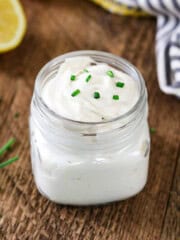 vegan sour cream in a jar with chives and lemon in the background.