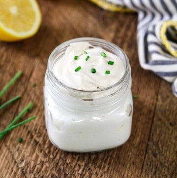 vegan sour cream in a jar with chives and lemon in the background.