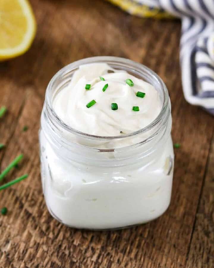 vegan sour cream in a jar with chives and lemon in the background.