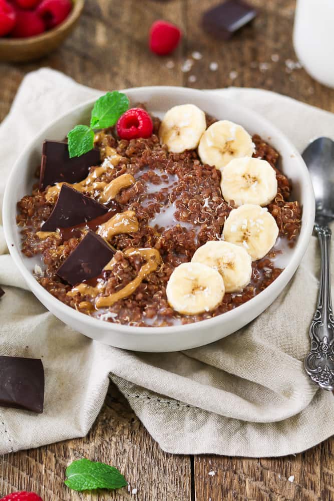 Quinoa Breakfast Bowl topped with banana coins, chocolate chunks and swirled peanut butter.