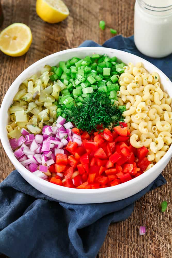 Chopped ingredients in a white bowl for vegan macaroni salad.
