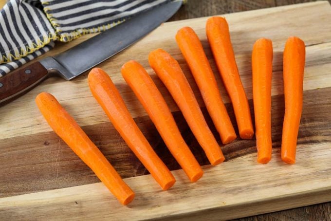 Eight cut & peeled carrots on a cutting board. 