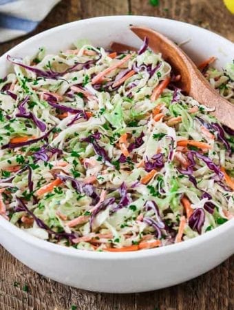 Vegan Coleslaw in a white bowl with a wooden spoon