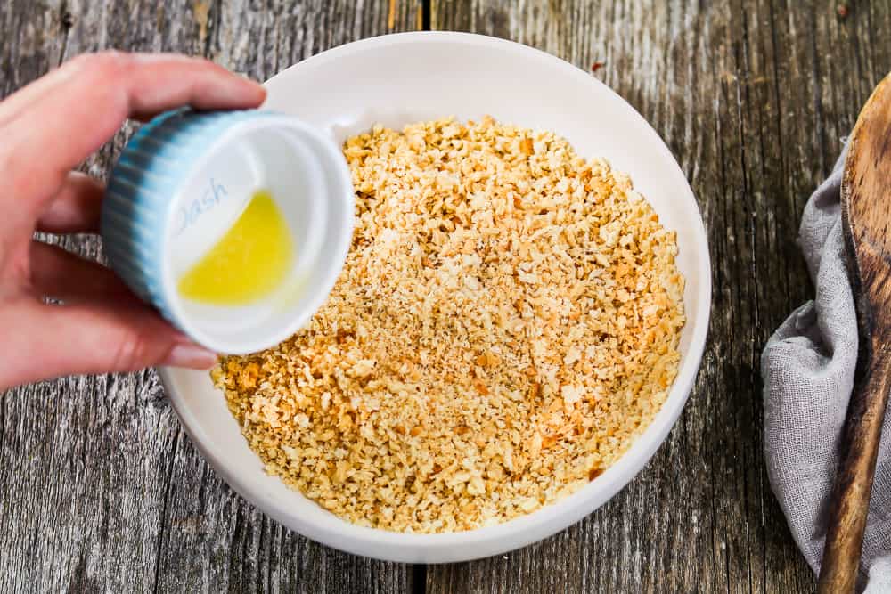 Pouring vegan butter onto panko breadcrumbs for the vegan cauliflower casserole topping.