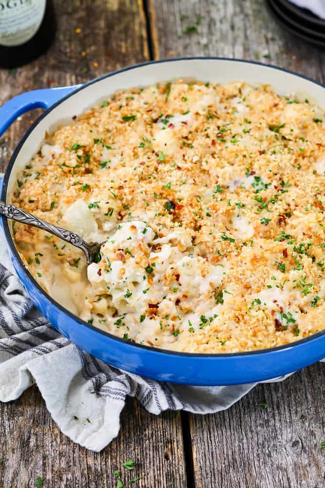 Vegan cauliflower casserole in a blue baking dish. Spoon inside and ready to scoop out. 