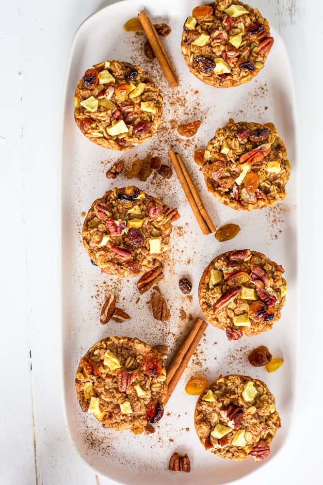 7 baked oatmeal muffins on a white serving tray. Cinnamon sticks in the middle. 