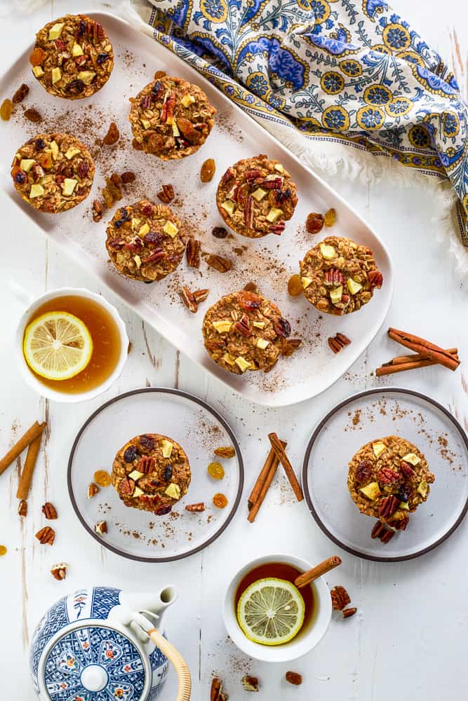 Overhead view of baked oatmeal muffins on a white serving tray. Tea with lemon on the side. 