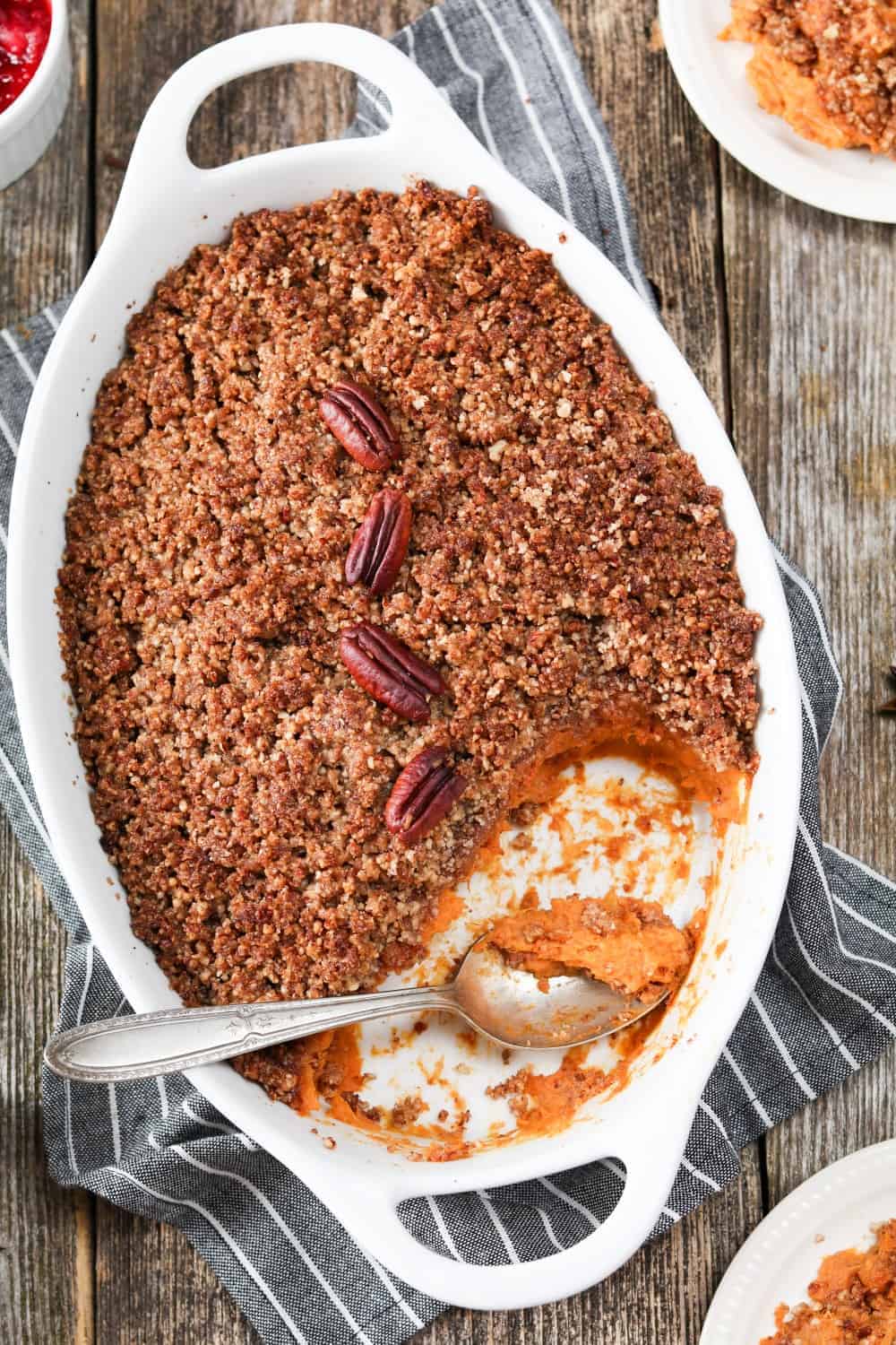 Fully baked sweet potato casserole in a white baking dish with spoon inside.