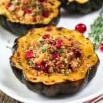 stuffed acorn squash on a white serving platter. Topped with fresh thyme.
