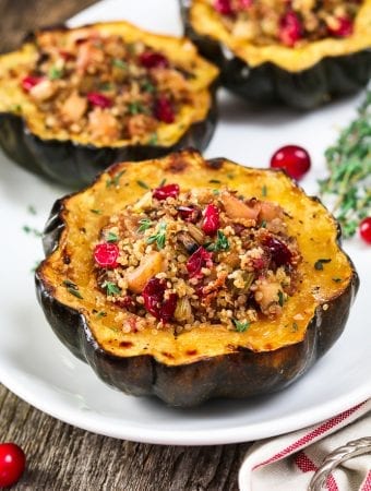 stuffed acorn squash on a white serving platter. Topped with fresh thyme.