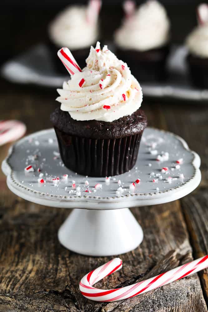 decorated chocolate cupcake on white cupcake stand. Crushed candy cane on the stand. 